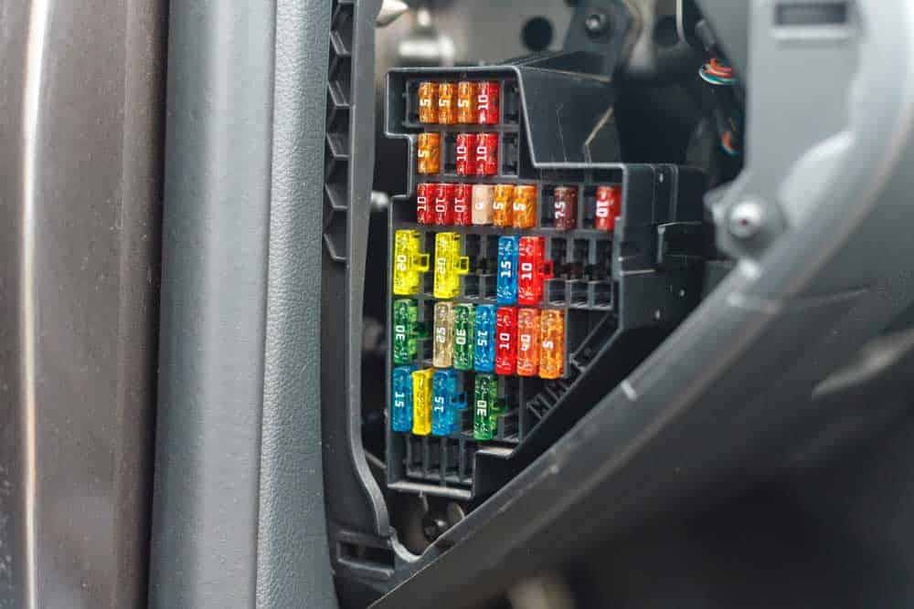 A car’s fuse box with multiple multi-colored fuses