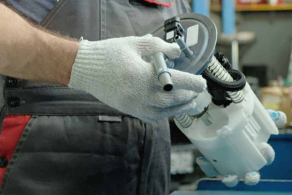 A qualified mechanic with a car's fuel pump.