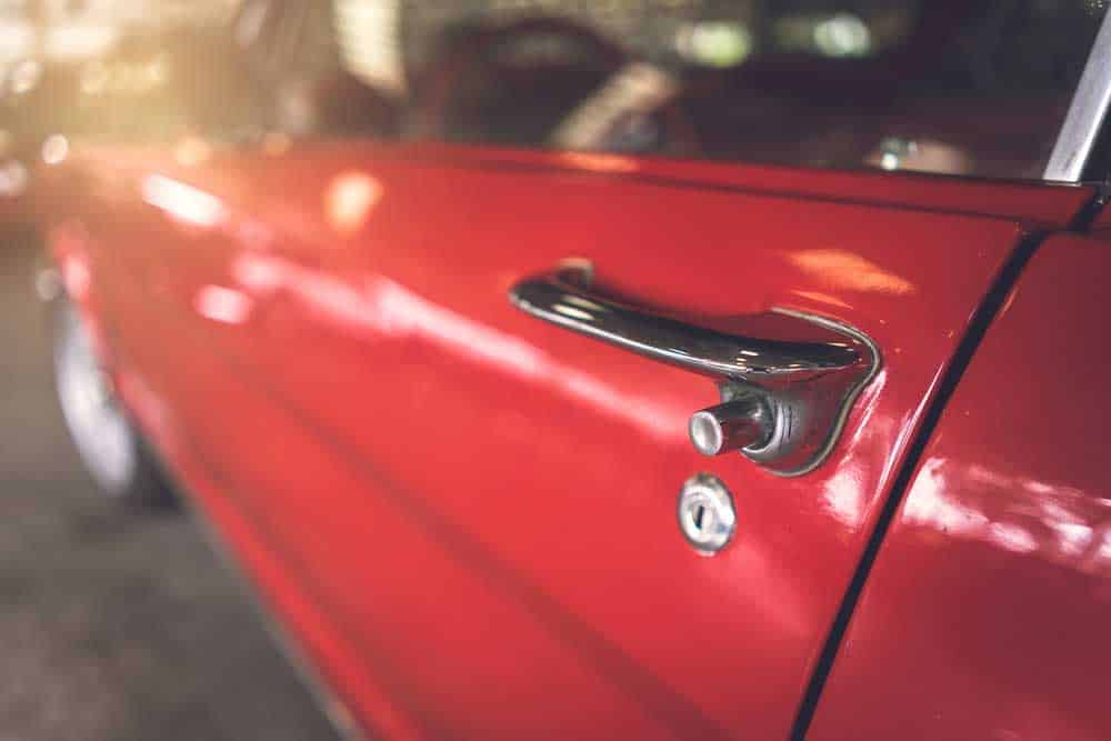 The door handle and lock of a red retro classic car