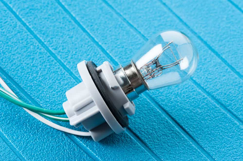 A car headlight socket with three electrical wires connected (green, white-green, and white wire)