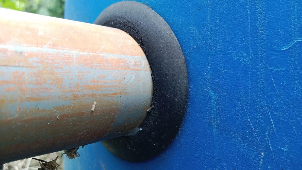 An insulation rubber grommet encases a pipe.
