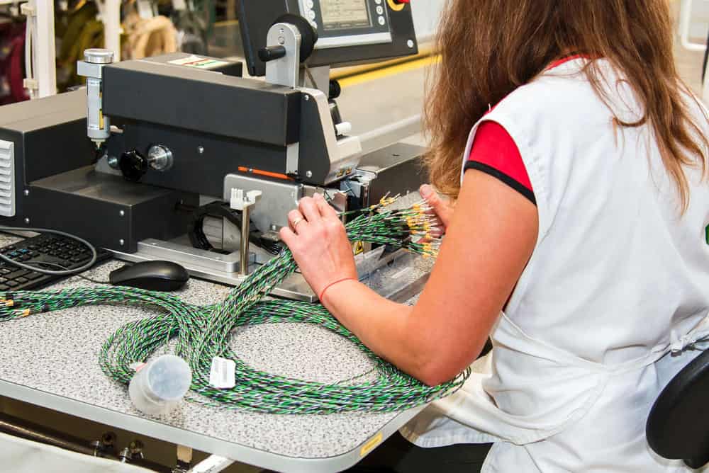 A factory worker testing the quality of wiring harnesses for cars