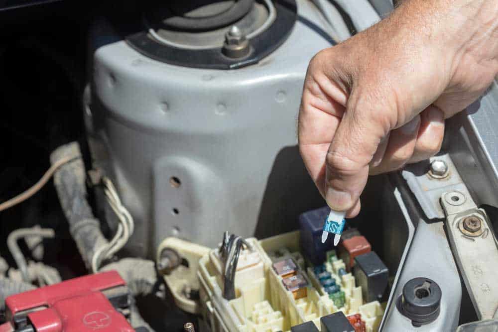 Auto mechanic checking car fuse